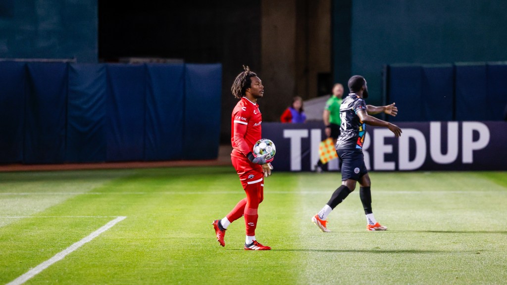 Kendall McIntosh holding a soccer ball on the field.
